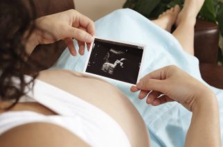 Pregnant woman sitting on sofa looking at her unborn baby's ultrasound scan